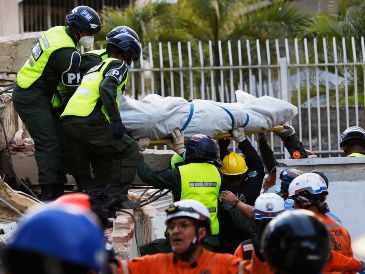 Rescatistas transportan un cuerpo recuperado de los escombros de un edificio derrumbado en Caracas, Venezuela. AP/P. Mattey