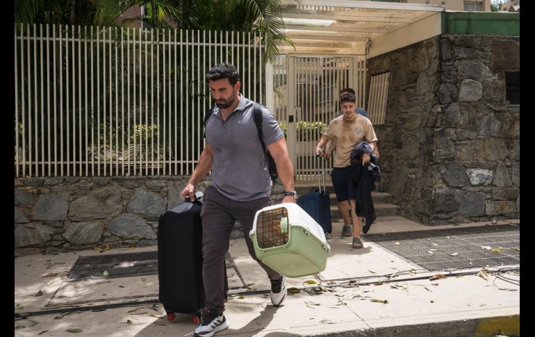 Personas salen de un edificio con pertenencias y mascotas este jueves, en el municipio Chacao en Caracas. EFE/B. Vergara
