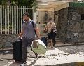 Personas salen de un edificio con pertenencias y mascotas este jueves, en el municipio Chacao en Caracas. EFE/B. Vergara