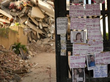 Avisos dejados por familiares que buscan a personas desaparecidas se exhiben en la entrada de un edificio destruido por los terremotos en La Guaira, Venezuela. AP/M. Delacroix