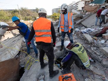 Integrantes de equipos de rescate realizan una búsqueda en los escombros de un edificio este lunes, en La Guaira Venezuela. EFE/ R. Peña