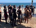 Jóvenes inmigrantes que duermen en la calle hacen fila para bañarse en la playa del Trampolín, tras acceder a Ceuta el pasado jueves. EFE/Reudan