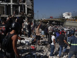 Personas caminan sobre los escombros de un edificio colapsado este lunes, en Cali (Colombia). Al menos 20 edificios sufrieron graves daños por consecuencia del terremoto de magnitud 7,4 que sacudió la mayor parte del país, con epicentro en la zona del Pacífico. EFE/ E. Guzmán