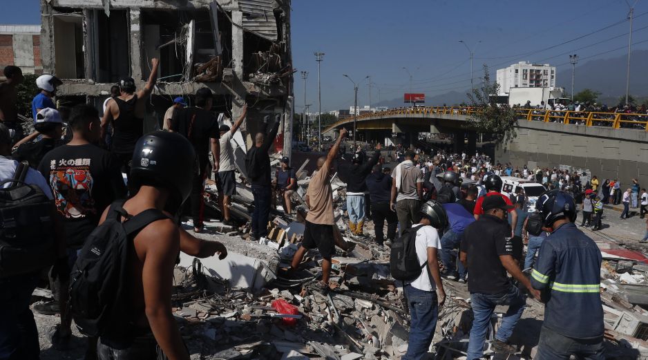 Personas caminan sobre los escombros de un edificio colapsado este lunes, en Cali (Colombia). Al menos 20 edificios sufrieron graves daños por consecuencia del terremoto de magnitud 7,4 que sacudió la mayor parte del país, con epicentro en la zona del Pacífico. EFE/ E. Guzmán