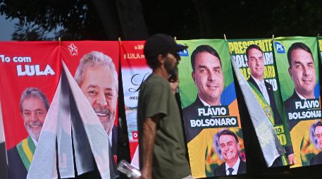 Un hombre camina frente a una tienda informal de banderas con la imagen del presidente de Brasil y candidato a la reelección, Luiz Inácio Lula da Silva, y del candidato presidencial, Flávio Bolsonaro. EFE/A. Borges